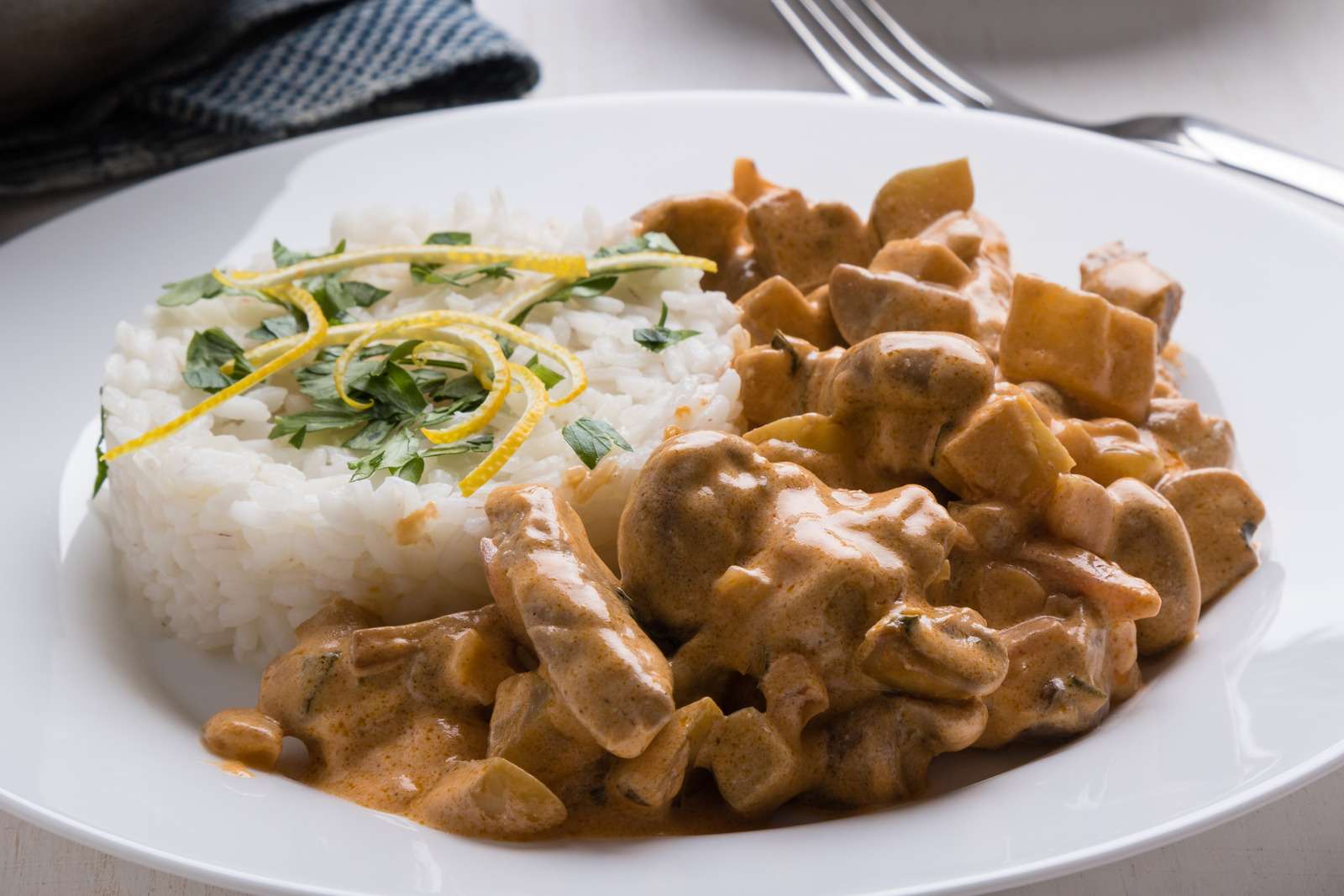 beef stroganoff with rice on white plate