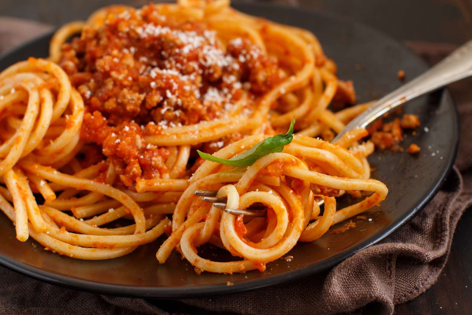 Spaghetti pasta with bolognese sauce on a dark table close up