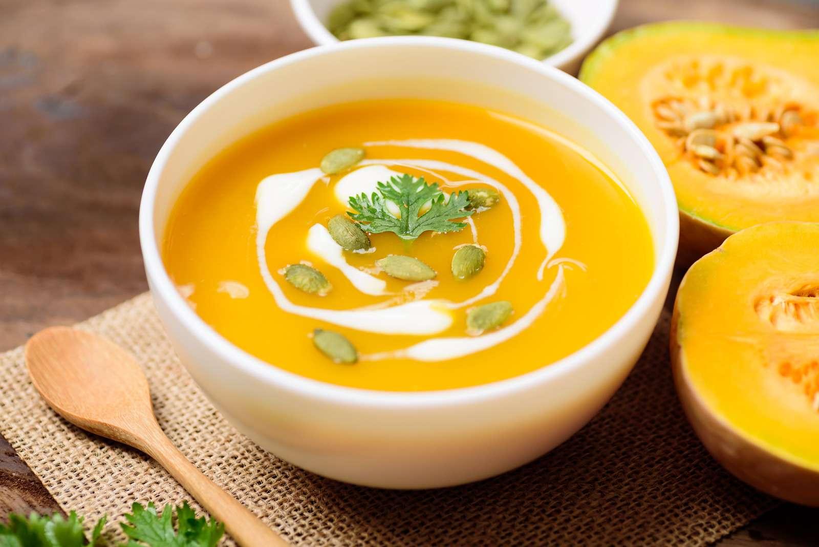 Butternut squash soup with pumpkin seed and cream in a bowl on wooden background